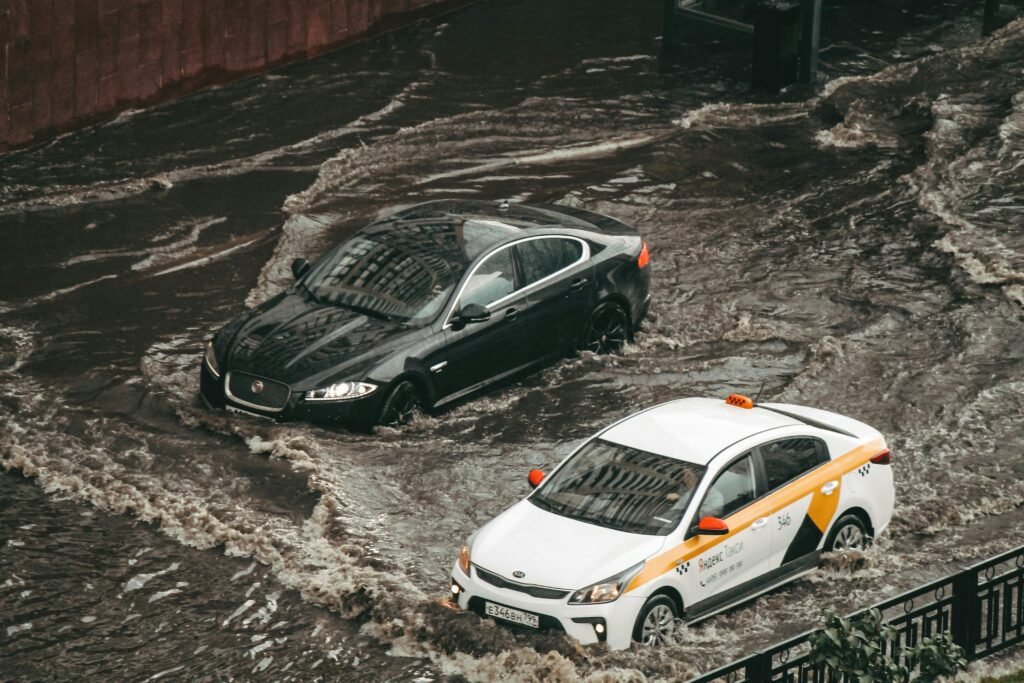 Buyer Beware: Navigating the Surge of 45,000 Flood-Damaged Cars in the 2025 Used Car Market Cars navigating through a flooded city street, showcasing urban chaos and weather impacts.